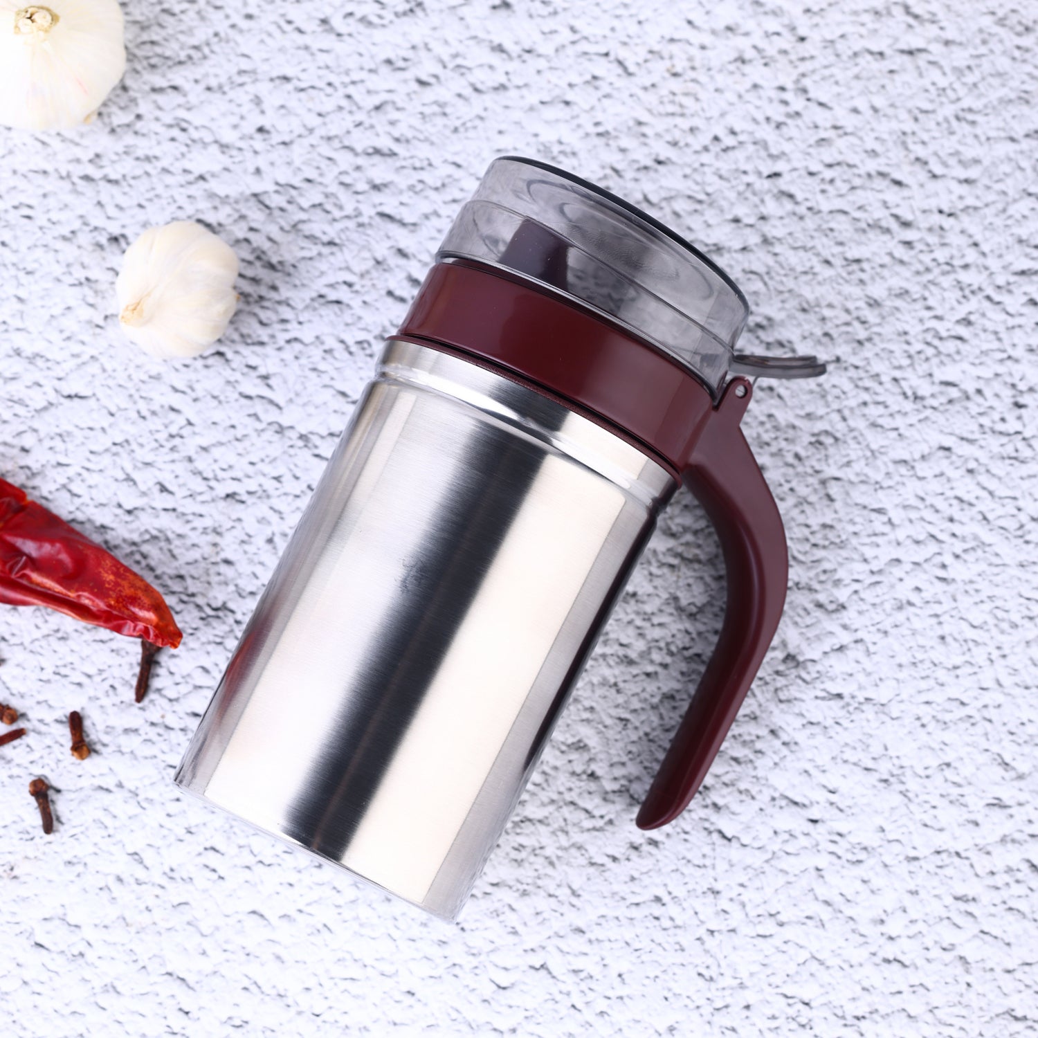 Sleek stainless steel oil dispenser with a small pouring nozzle on a white background.