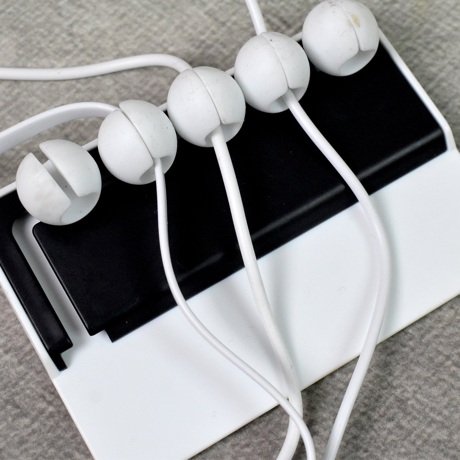 Adhesive cable holder attached to a wall for workspace organization