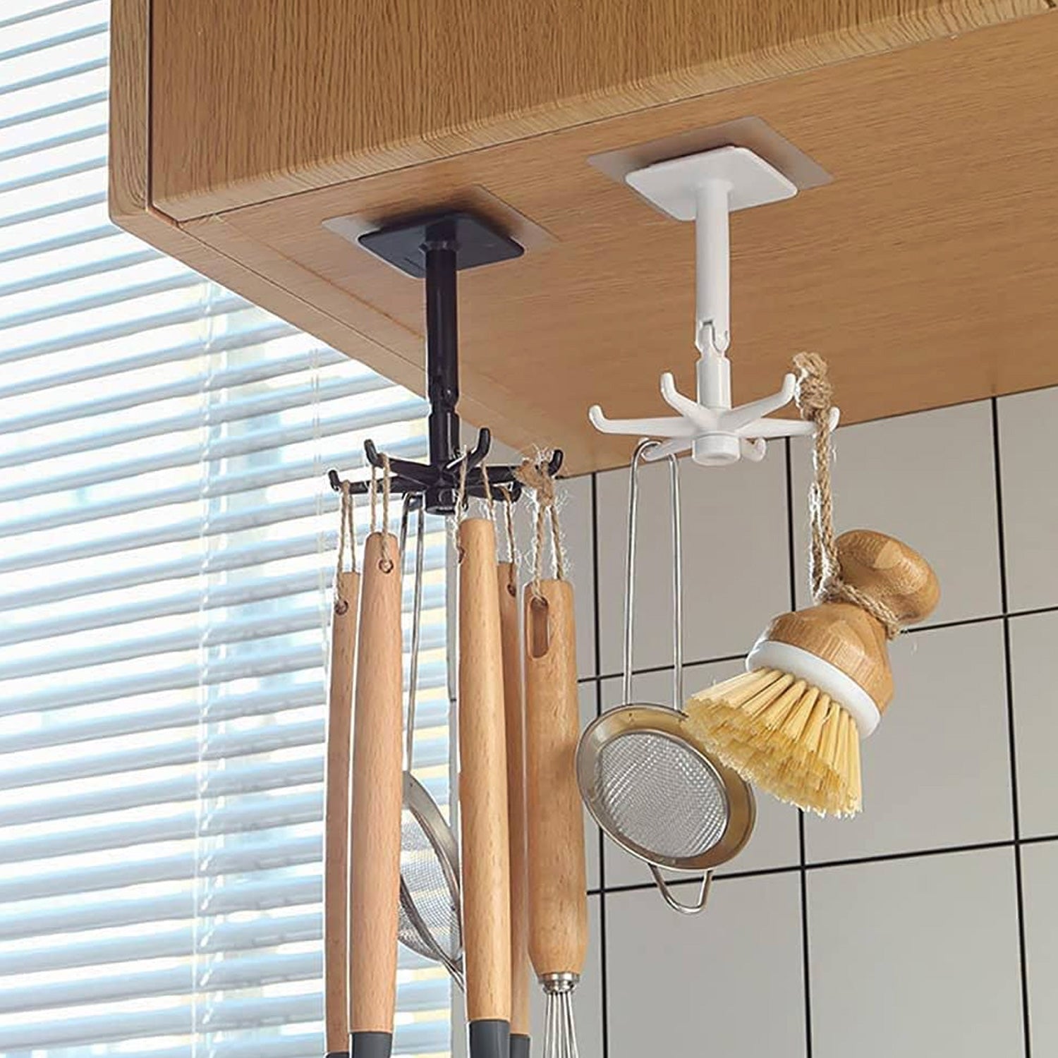 A hand demonstrating the 360-degree rotation of the self-adhesive wall hook.