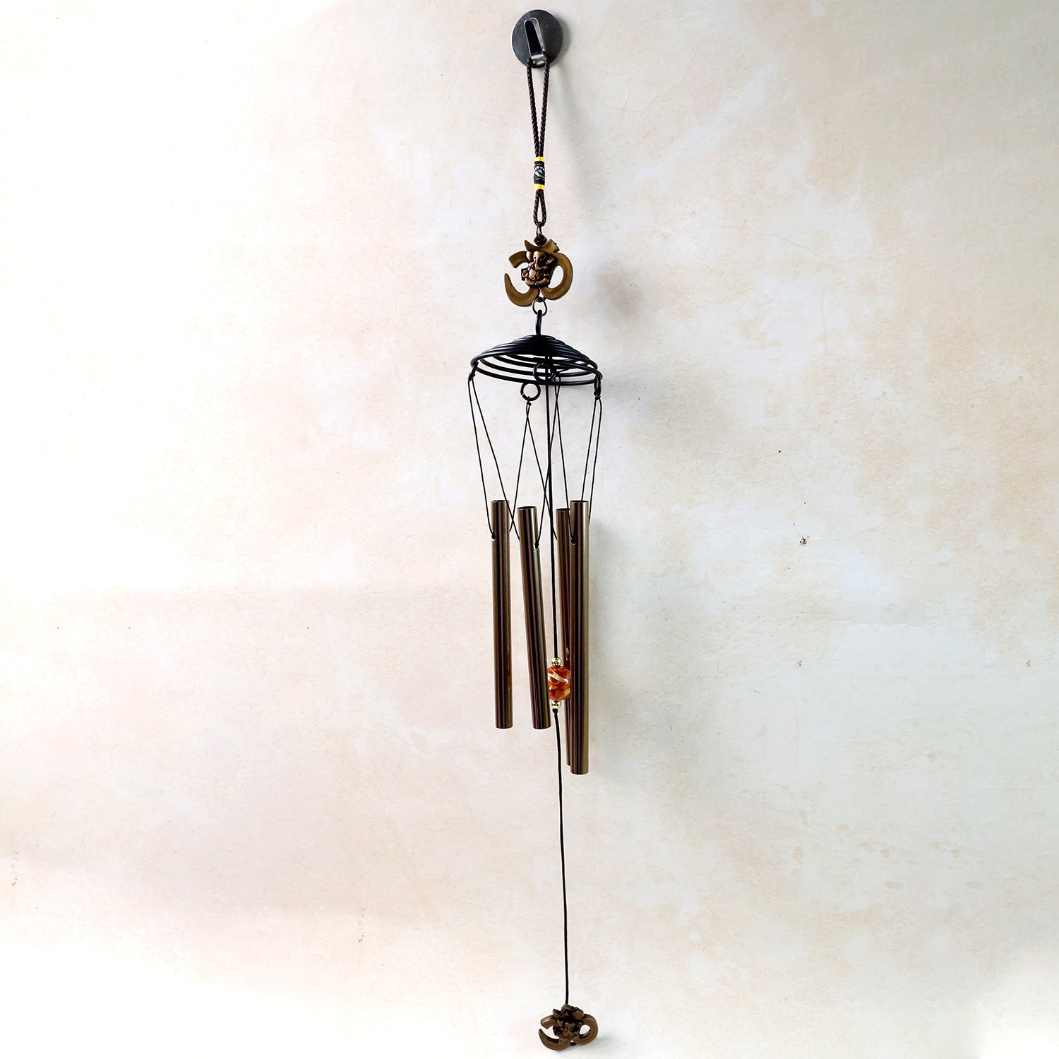 Metal Om symbol wind chime hanging on a wooden porch