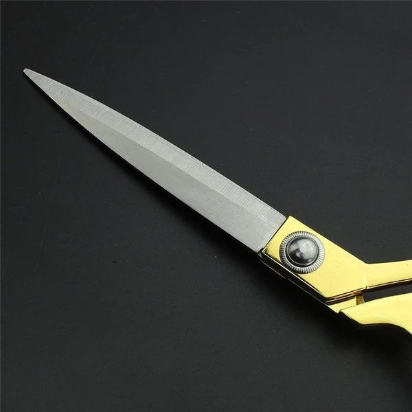 Pair of sharp golden tailoring scissors on a clean surface.
