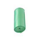 Multiple rolls of green biodegradable trash bags on a clean white surface.