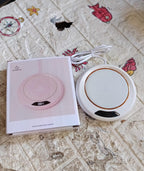 A hand placing a mug onto the USB mug warmer on a home office desk.