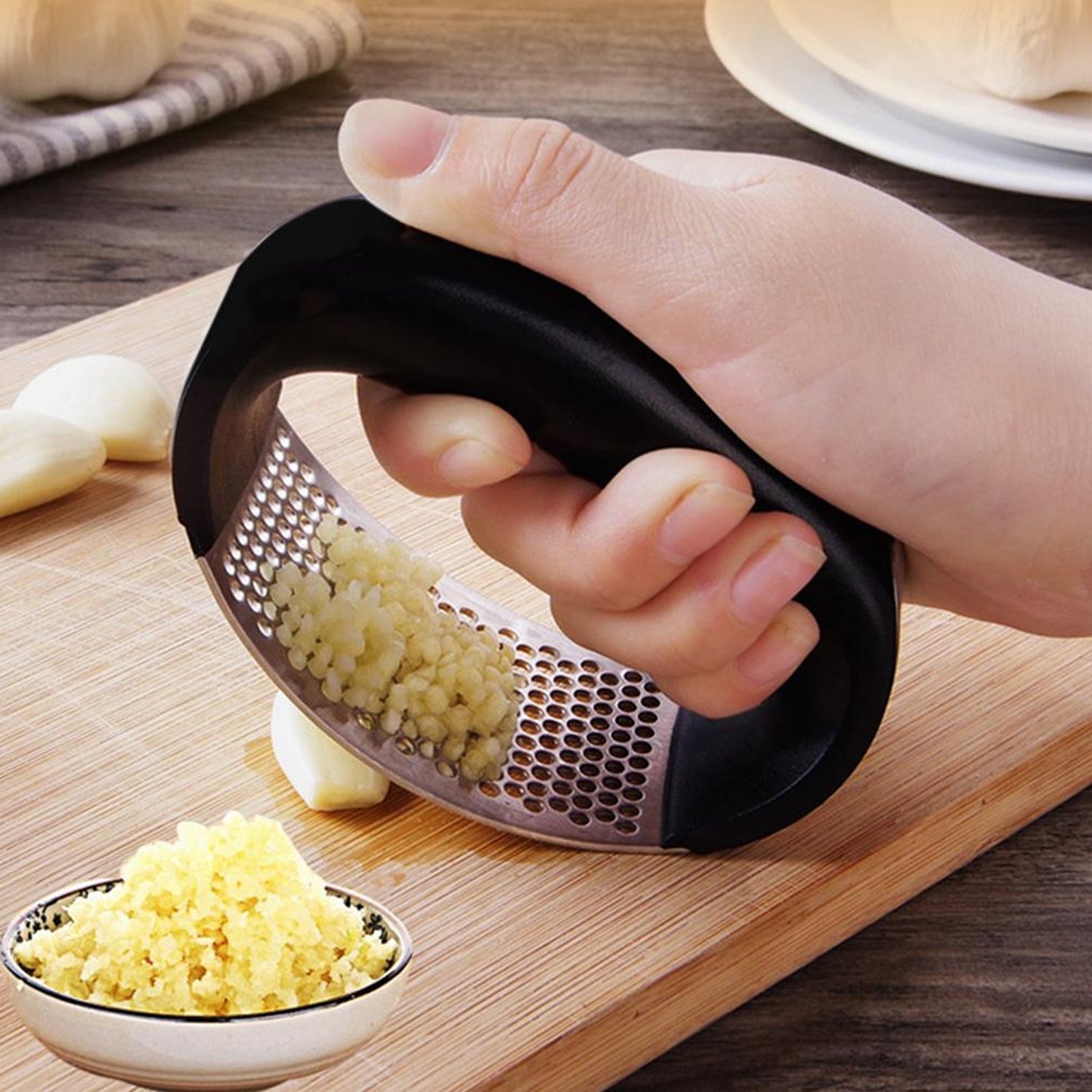 Ergonomic stainless steel garlic press tool on a clean white background.