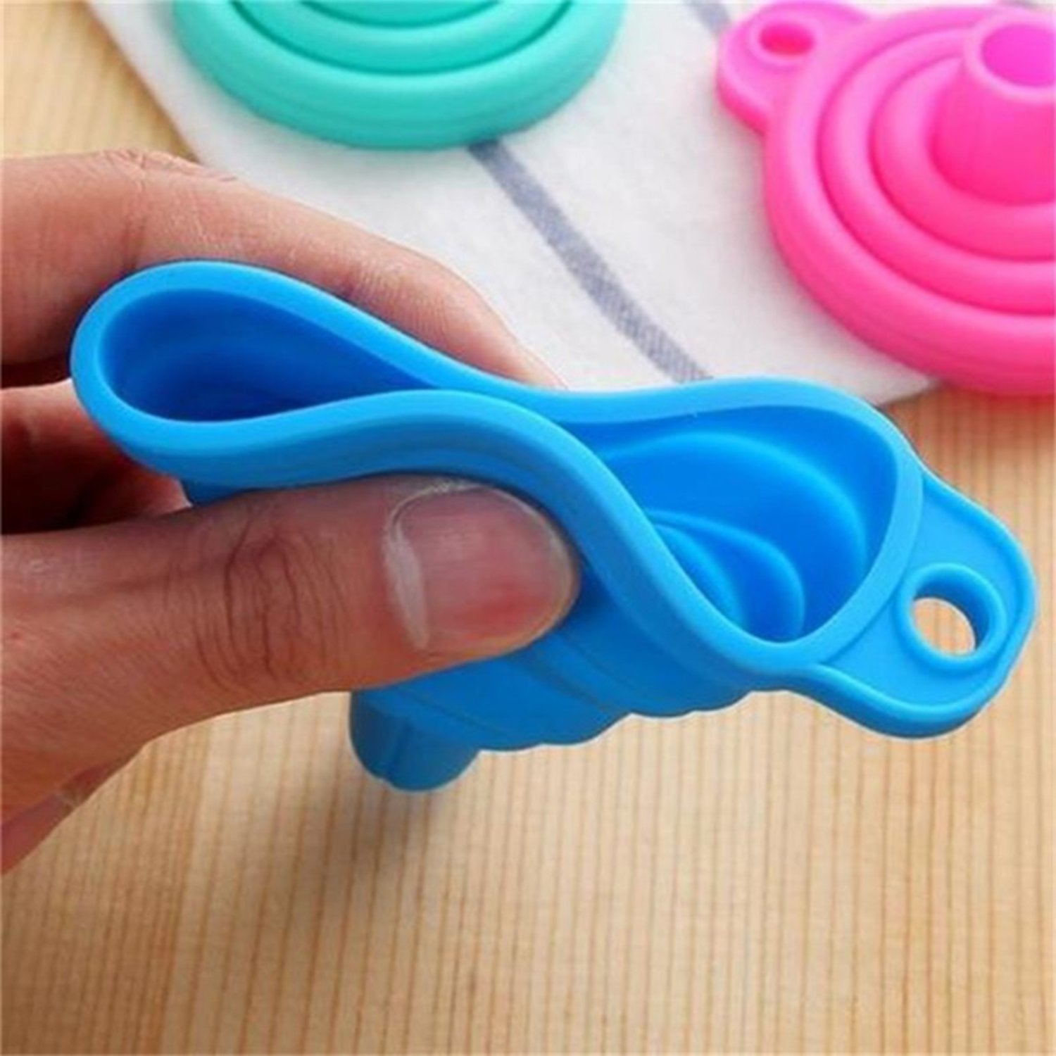 Red silicone funnel pouring oil into a narrow-necked bottle, preventing spills.