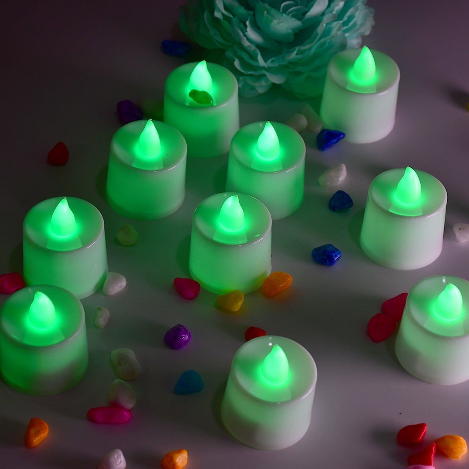 Green flameless LED tealights glowing softly on a dark surface.
