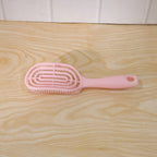 Woman brushing her hair with pink curved styling brush