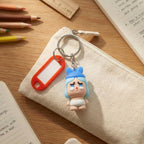 Cute figure keychain featuring a baby cartoon with a label for identification.