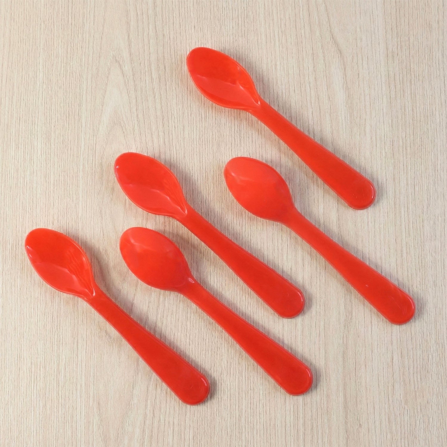 Five white plastic spoons fanned out on a clean surface, highlighting their simple design.