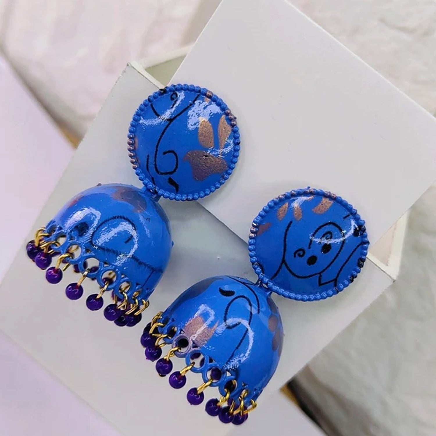 Vibrant blue Jhumka Earrings with intricate golden patterns, suitable for a pop of color in ethnic ensembles.